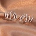 Schicke silberne Krallen-Ohrringe mit Zirkonia-Steinen auf elegantem Seidenhintergrund - Ohrclips / Silber