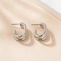 Minimalist double-layered silver C-shaped hoop earrings on a warm beige background - Silver
