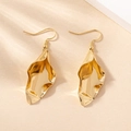 Makroaufnahme der goldenen Blattstruktur und des modernen unregelmäßigen Ohrring-Designs - Gold