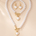Detail of elegant pearl jewelry set with heart pendants and golden OT toggle clasps - White