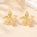 Close-up of golden five-petal flower stud earrings with matte metal texture on stone - Gold