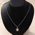 Elegant silver sun face pendant necklace displayed on a black neck mannequin - Silver