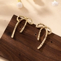 Detailed close-up of golden bow earrings with textured hammered finish and long tassels - Gold