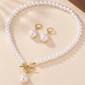 Set elegante di collana e orecchini di perle dorate con chiusura a T su fondo sabbia - Bianco