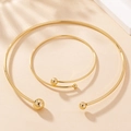 Details von minimalistischem goldfarbenem Halsreif und Armreif mit Kugelenden - Gold