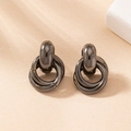 Macro detail of gunmetal multi-layered interlocking hoop earrings on warm beige background - Black Nickel