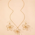 Dettaglio del set di gioielli floreali in filo dorato con collana e orecchini a trama cava - Oro