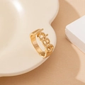 Detailed view of a gold KISS letter cutout ring placed on a minimalist ceramic tray - Gold