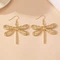 Detailed close-up of golden dragonfly drop earrings featuring intricate hollow-out wings - Gold