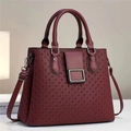 Detail view of burgundy leather handbag featuring woven embossed texture and metallic hardware - Wine Red