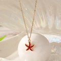 Collier avec pendentif étoile de mer dorée en émail rouge sur fond de nacre irisée - Bordeaux