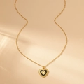 Détail d'un collier doré vintage avec pendentif cœur émaillé noir et centre texturé - Noir