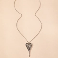 Macro-detail van zilveren hartvormige hanger met gehamerde textuur aan de ketting - Zilver