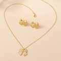 Dettaglio macro del set collana e orecchini a fiocco dorato con trama a righe sottili - Oro