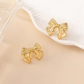 Elegant gold bow earrings with polished finish on a minimalist ceramic shell tray - Gold