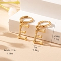 Detailed close-up of golden letter E bamboo texture earrings on a minimalist pedestal - Letter E Style