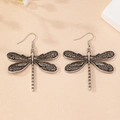 Detailed macro view of vintage dragonfly earrings with intricate silver wings and ear hooks - Antique Silver