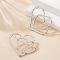 Minimalist silver double heart stud earrings with textured finish on beige background - Silver