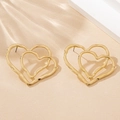 Macro detail of gold double heart earrings featuring an irregular hammered metal texture - Gold
