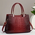 Detailed view of the dark red crocodile embossed leather texture and gold hardware on bag - Red
