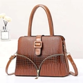 Close-up of brown crocodile texture pattern and gold hardware on woman's crossbody bag - Earthy Yellow