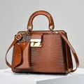 Brown faux lizard leather handbag set with gold spherical lock on a white pedestal - Yellow