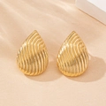 Primer plano de pendientes de gota dorados con textura metálica de rayas onduladas - Dorado