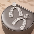 Silver hammered metal geometric arch earrings on elegant jewelry box with soft shadows - Silver