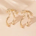 Nahaufnahme eleganter goldener Schleifen-Ohrstecker mit fließendem Banddesign - Gold
