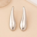 Macro view of silver water drop earrings with unique textured metallic finish and sleek curves - Silver