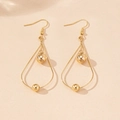 Détail de boucles d'oreilles pendantes dorées en forme de goutte avec perles métalliques - Jaune d'Or