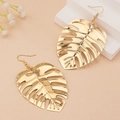 Goldene Monstera-Blatt-Ohrringe mit Hohlmuster auf minimalistischem Display - Goldgelb