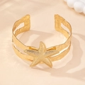 Detailed close-up of golden starfish arm cuff with textured bands for beach vacation wear - Gold Yellow