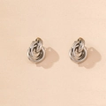 Detail der silbernen Knoten-Ohrstecker mit hohlem, ineinandergreifendem Ringdesign - Platinfarbene runde Ohrstecker