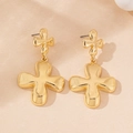 Detail view of irregular gold-plated clover earrings on a textured beige surface - Gold Yellow