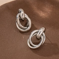 Macro detail of silver polished interlocking triple ring earrings on a textured background - Platinum Oval Stud Earrings