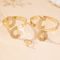 Gedetailleerde weergave van gouden infinity armbanden en bijpassende ring op display - Gouden 3-delige Set (Inclusief 2 Armbanden + 1 Ring)