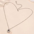 Collana con ciondolo a nodo intrecciato argento e cristalli su sfondo neutro testurizzato - Collana Pendente Nodo Spirale Zirconia / Argento