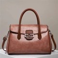 Detail view of pink tote bag with brown leather handles and decorative V-shaped metal buckle - Pink