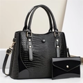 Macro detail of the glossy lizard embossed texture and golden metal buckle on black tote - Two-Piece Set / Black