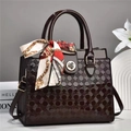 Détail d'un sac à main vernis bordeaux avec texture géométrique et foulard en soie - Café