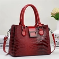 Detail der roten Handtasche aus Lackleder mit Eidechsenprägung, Farbverlauf und Silberschnalle - Rot