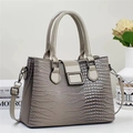 Détail d'un sac à main gris texture lézard avec boucle métallique et double poignée - Gris