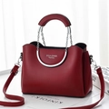 Close-up of burgundy leather crossbody bag with silver round handles and chain link detail - Burgundy