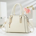 Elegant cream tote bag with V-shaped woven texture and floral charm on a white stand - Off-white