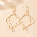Close-up of elegant gold twisted geometric earrings on a textured neutral background - Gold