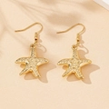 Detail of golden starfish earrings with textured surface and elegant fish hook design - Starfish Hook Style / Gold Yellow