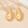 Detailed macro shot of irregular golden lava stud earrings on a textured stone base - Gold Irregular Stud Earrings