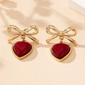 Nahaufnahme der eleganten Schleifenohrringe mit Herzanhängern in Rot und Gold-Finish - Burgunderrot