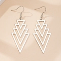Detailed close-up of layered silver triangle drop earrings on beige textured background - Silver